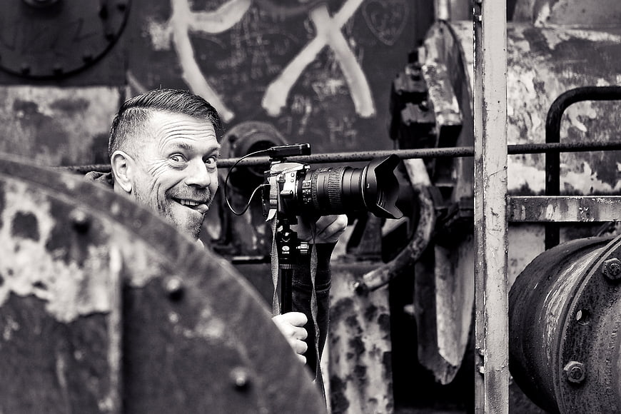 Man with DSLR Camera Making Funny Face in Industrial Setting