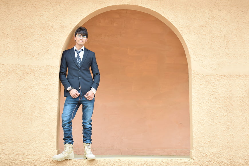 Young man in suit and jeans standing in archway