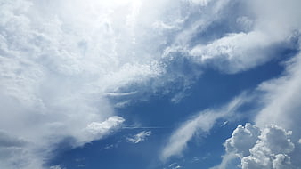 Dramatic blue sky with white clouds and airplane contrail