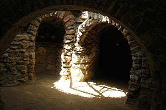 Sunlight streaming through stone arches in a rustic cave interior