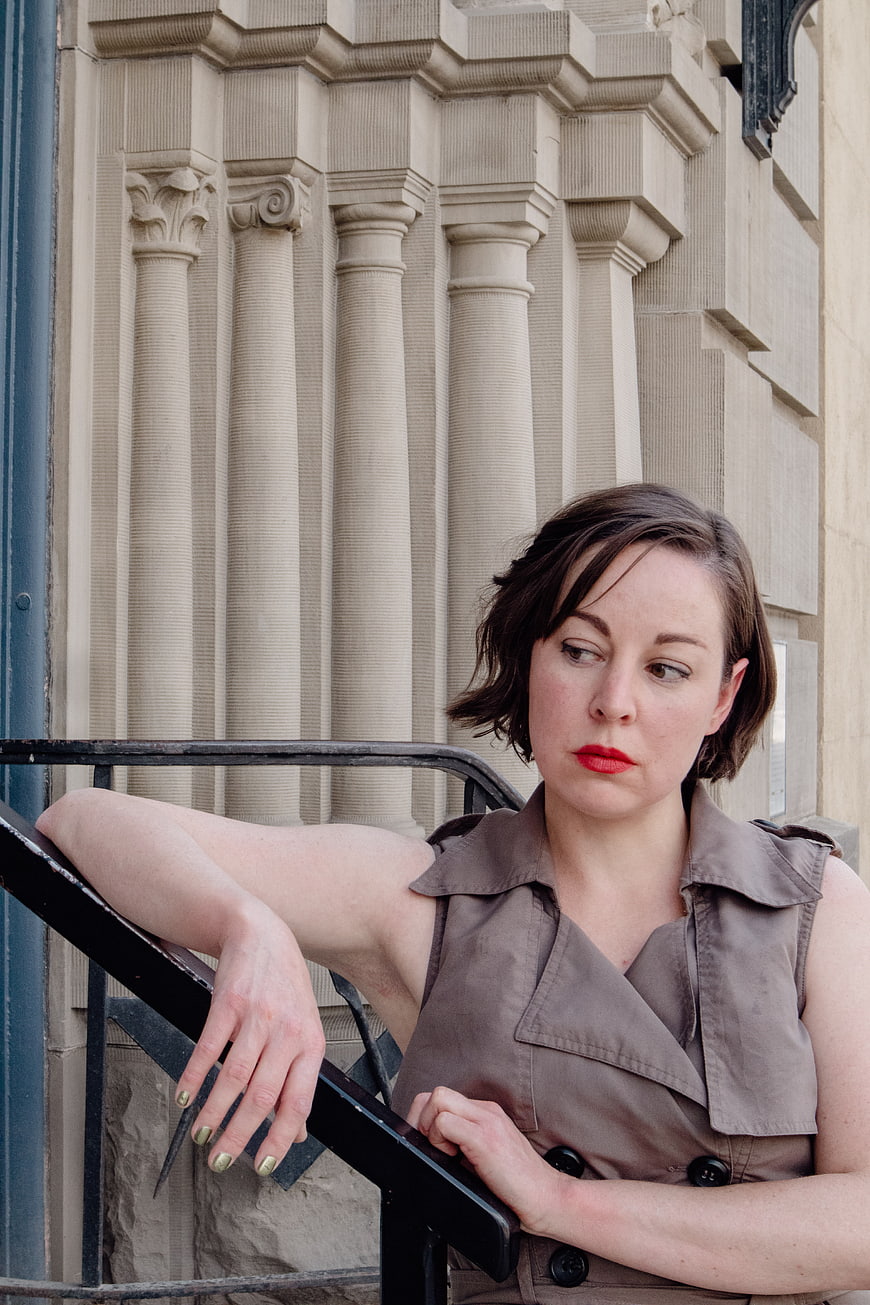 Woman in beige trench coat leaning on railing