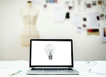 Laptop with light bulb screen in creative fashion design studio workspace