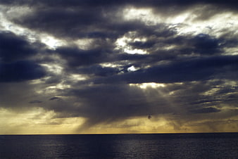 Dramatic stormy seascape with sun rays breaking through clouds