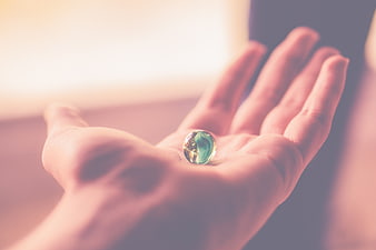 Hand holding a green glass marble with soft focus background