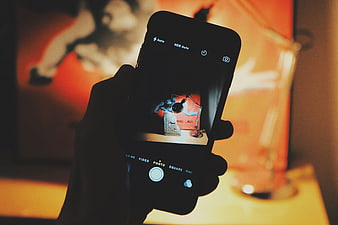 Hand holding smartphone taking photo of desk lamp