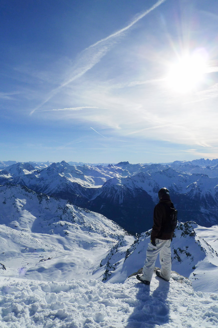 Skier standing on snowy mountain peak overlooking alpine range