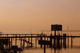 Silhouette of wooden pier at sunset over calm lake