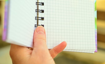 Hand Holding Open Grid Notebook With Blank Pages