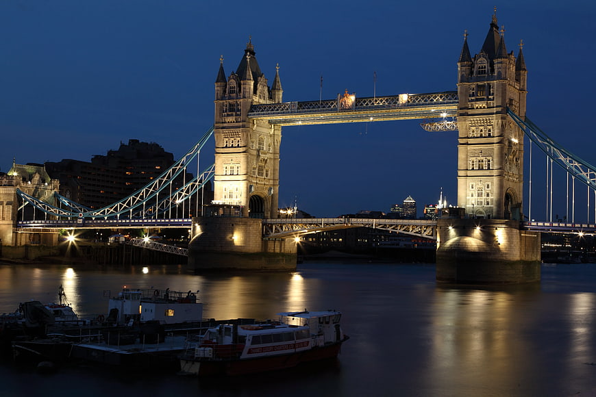 London Tower Bridge illuminated at night with boats on the Thames
