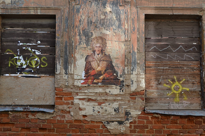Weathered Portrait on Abandoned Brick Wall with Graffiti