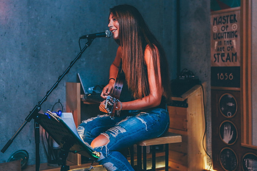 Female singer playing acoustic guitar on stage