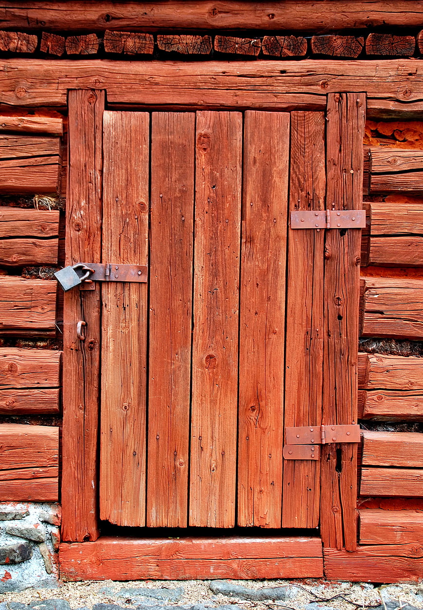Rustic Red Wooden Door with Padlock on Log Cabin