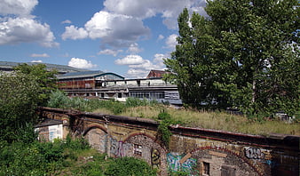 Abandoned industrial brick viaduct with graffiti and overgrown nature