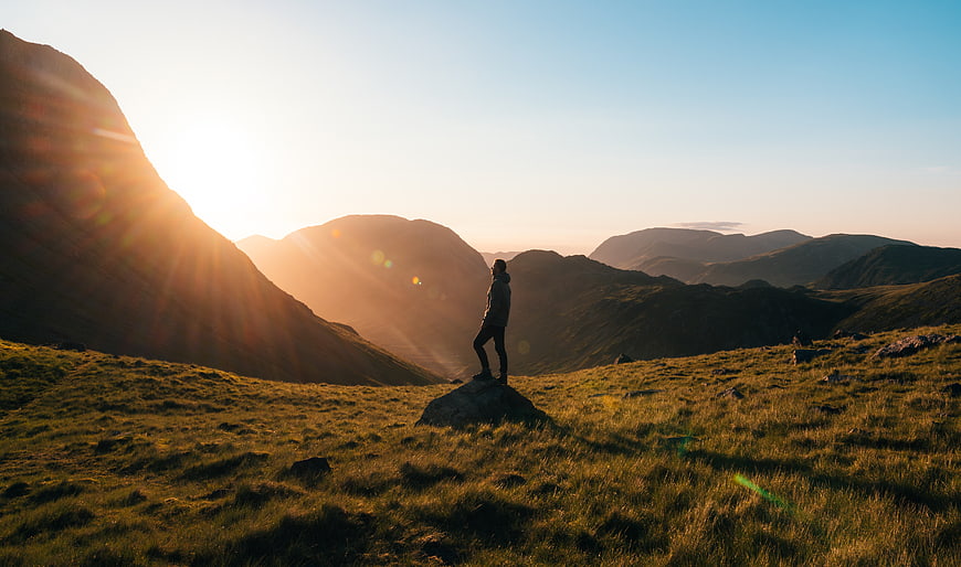 Silhouette of Hiker on Mountain Peak at Sunrise