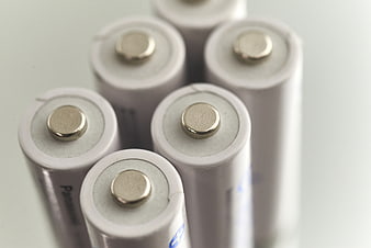 Close-up of white cylindrical batteries with positive terminals