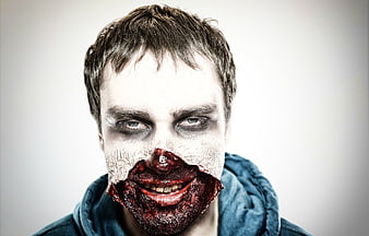 Zombie man portrait with cracked white face paint and bloody mouth