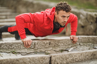 Athletic Man Doing Push-Ups in Red Hoodie Outdoors