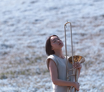 Woman holding trombone in field of white flowers
