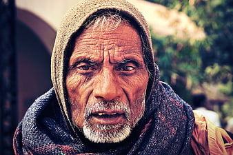 Close-up portrait of elderly Indian man with hooded scarf