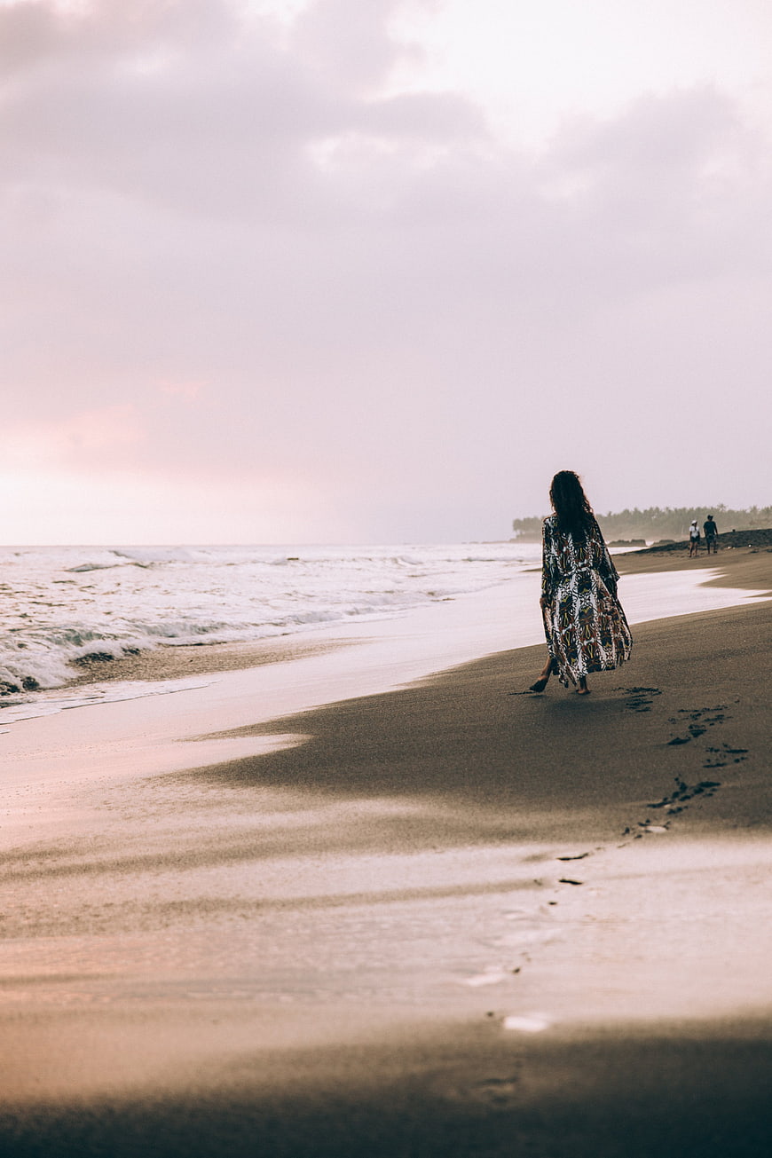Woman Walking on Sandy Beach with Footprints