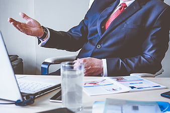 Businessman in Suit Gesturing at Office Desk