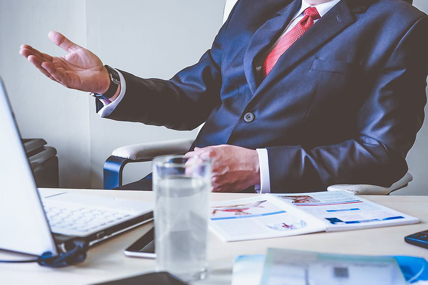 Businessman in Suit Gesturing at Office Desk