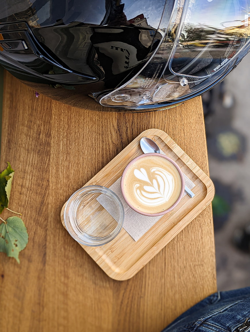 Top view of latte art coffee and motorcycle helmet on wooden table