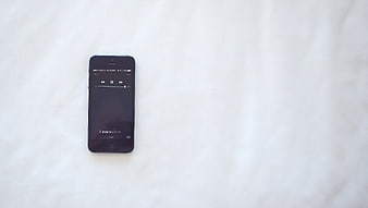 Black smartphone on white textured background with music player