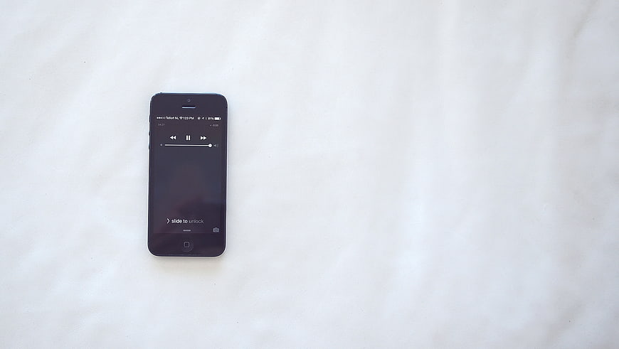 Black smartphone on white textured background with music player