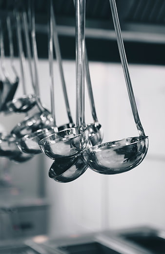 Shiny metal ladles hanging in a professional kitchen