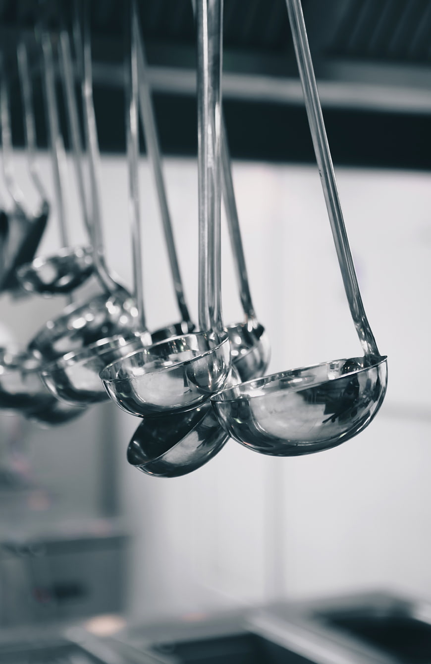 Shiny metal ladles hanging in a professional kitchen