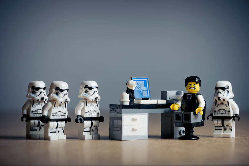 Lego stormtroopers confronting angry businessman at office desk