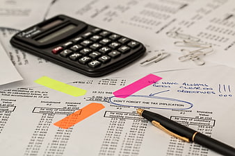 Financial documents with calculator and pen on desk