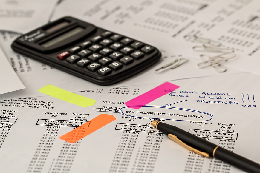 Financial documents with calculator and pen on desk