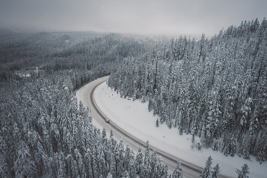 Aerial View of Snowy Forest Road with Car