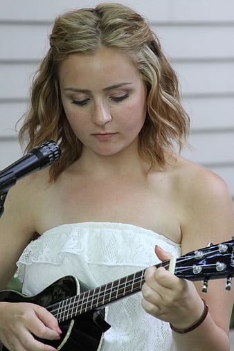 Young Woman Playing Ukulele and Singing into Microphone