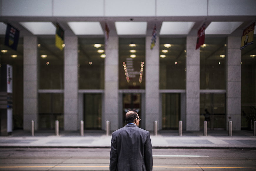 Man in Suit Standing Before Corporate Building Entrance