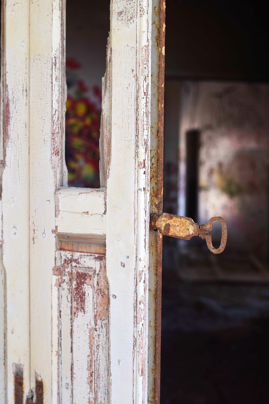 Rusty latch on weathered white wooden door frame