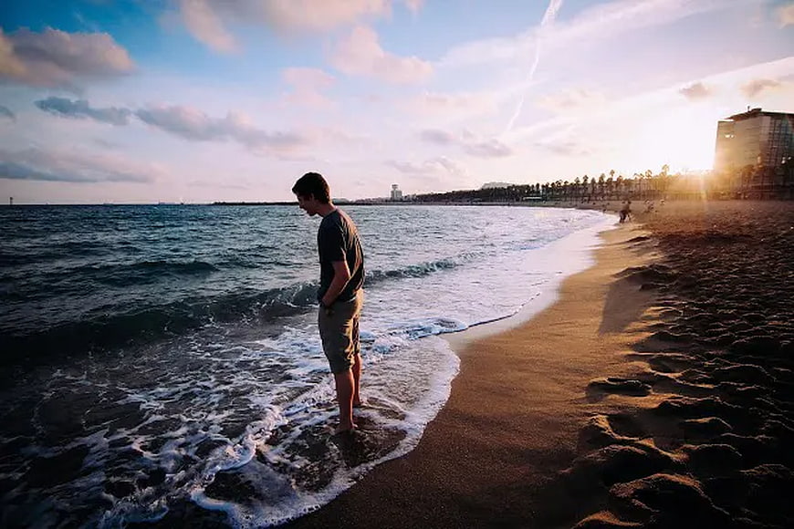 Man Standing in Ocean Waves at Sunset Beach