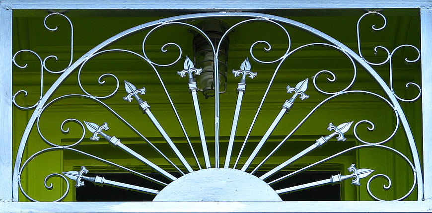 White wrought iron fanlight with fleur-de-lis design
