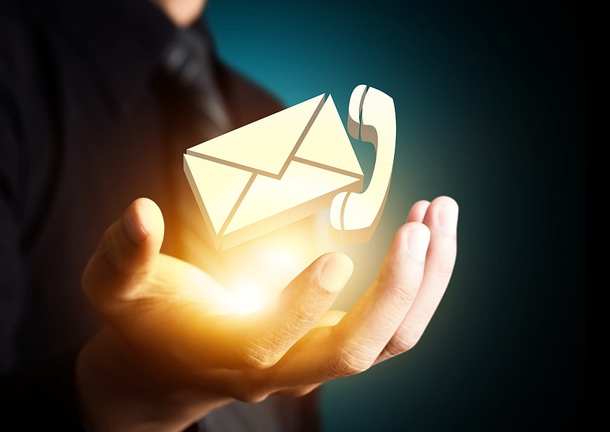 Businessman holding glowing email and phone icons in hand