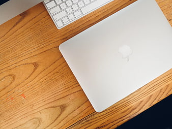 Closed Silver Laptop on Wooden Desk with Keyboard
