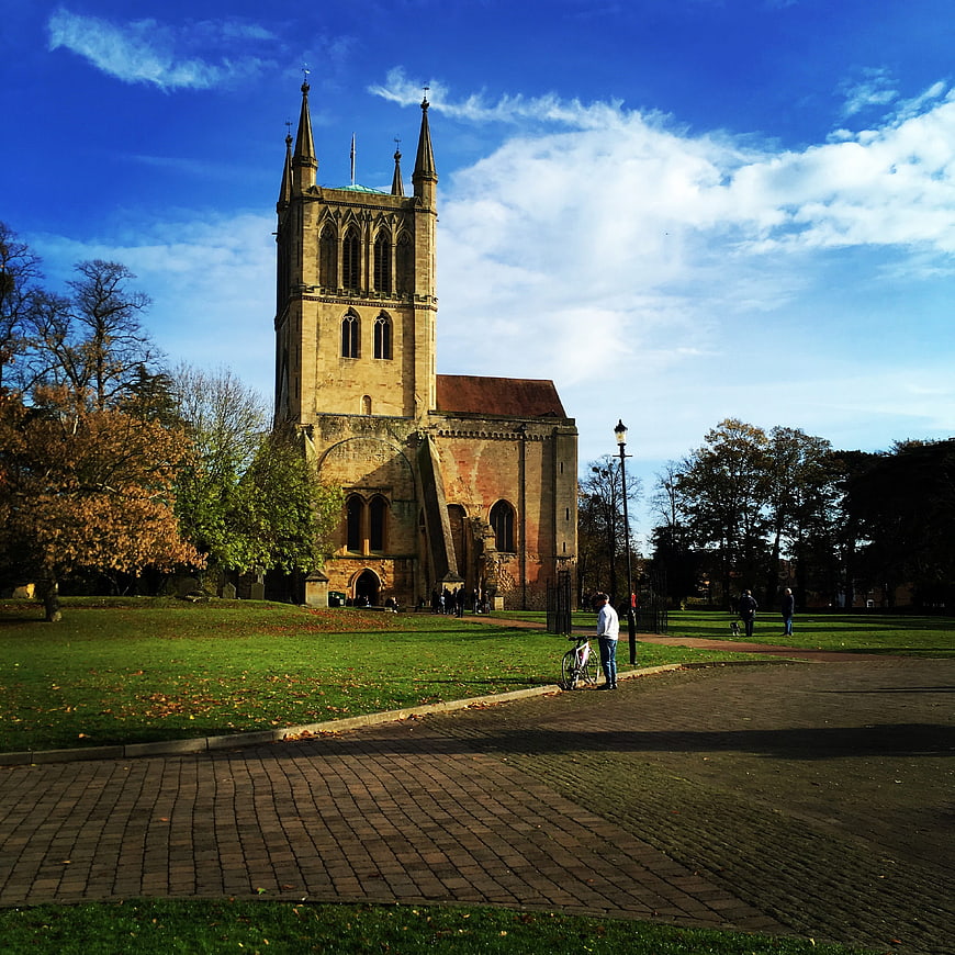 Pershore Abbey in autumn park with blue sky