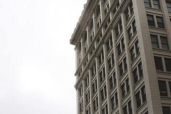 Low angle view of beige building facade against white sky