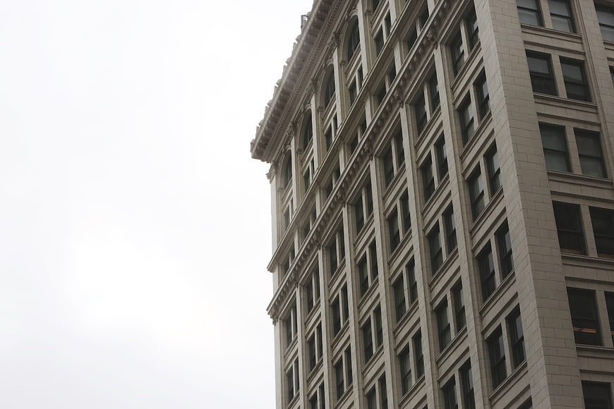Low angle view of beige building facade against white sky