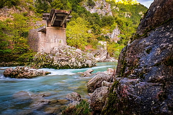 Abandoned concrete bridge over turquoise river in rocky gorge
