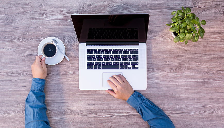 Top View of Hands Working on Laptop with Coffee