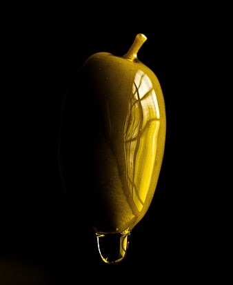 Golden olive oil drop shaped like an olive on black background