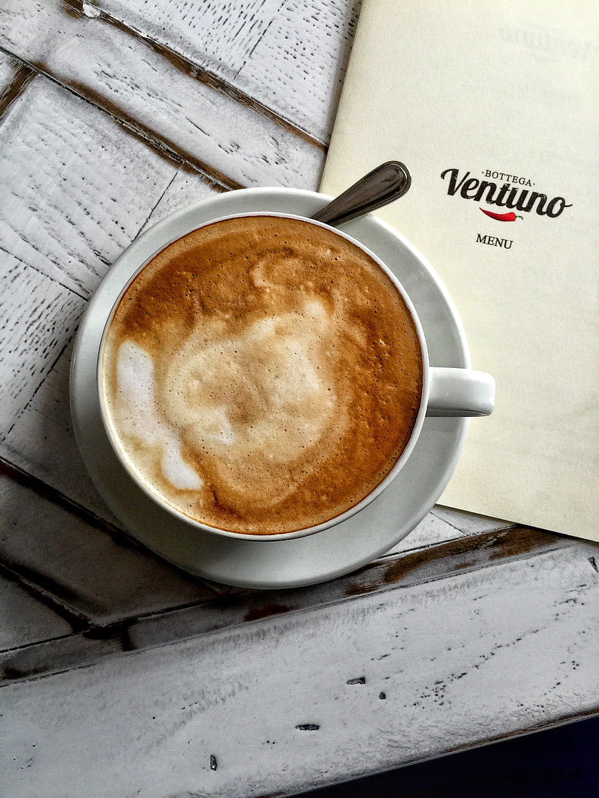 Flat lay cappuccino on rustic white wooden table with menu