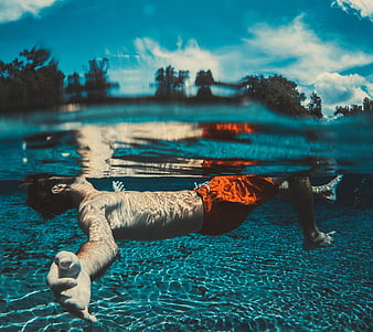 Man Floating Underwater In Clear Blue Water